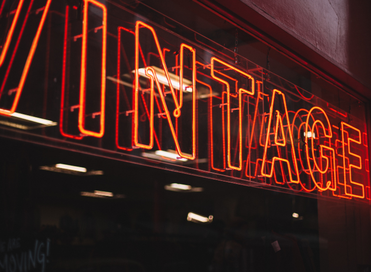 A red neon sign that says "vintage" hangs in a window